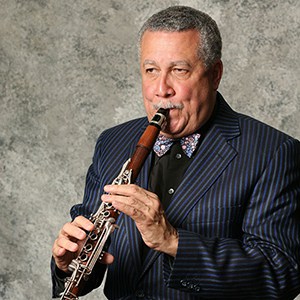 Paquito D'Rivera in blue pin stripes playing clarinet