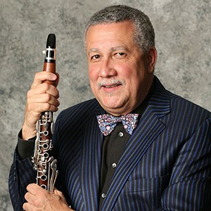 Paquito D'Rivera in blue pin stripes holding clarinet