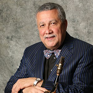 Paquito D'Rivera in blue pin stripe jacket holding saxophone