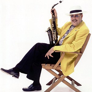 Paquito D'Rivera in yellow jacket holding saxophone