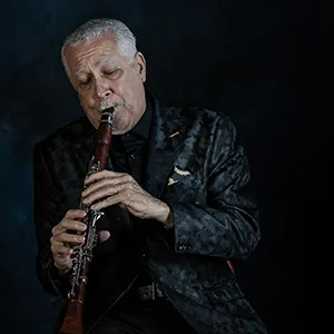 Paquito D'Rivera on Clarinet with black background looking down